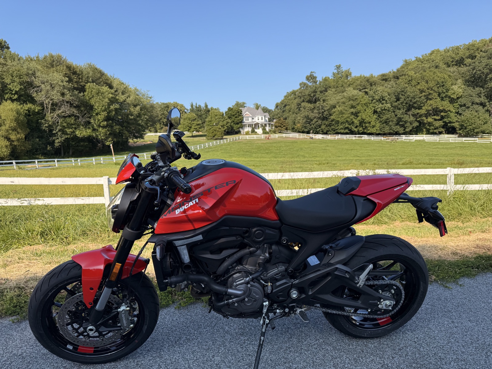 A new red 2026 Ducati Monster+ parked by a white fence, the bike I traded into after my 821 was damaged